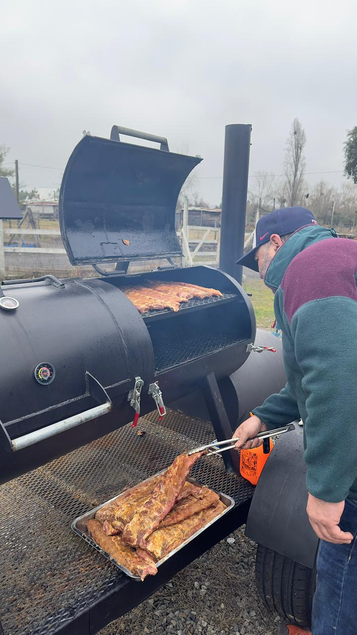 Pitmaster girando costillas sobre la parrilla