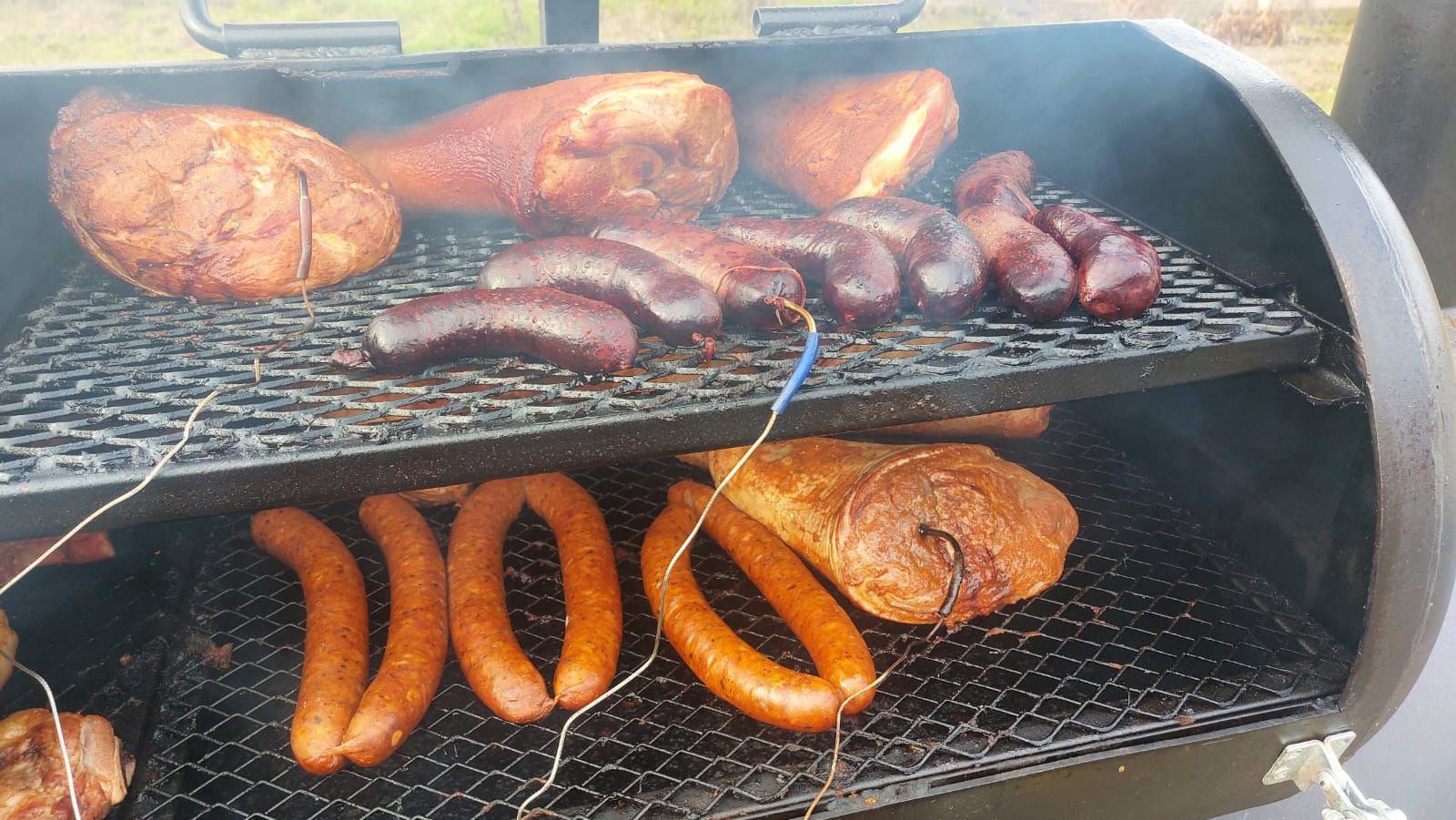 Longanizas y piernas ahumándose sobre la parrilla